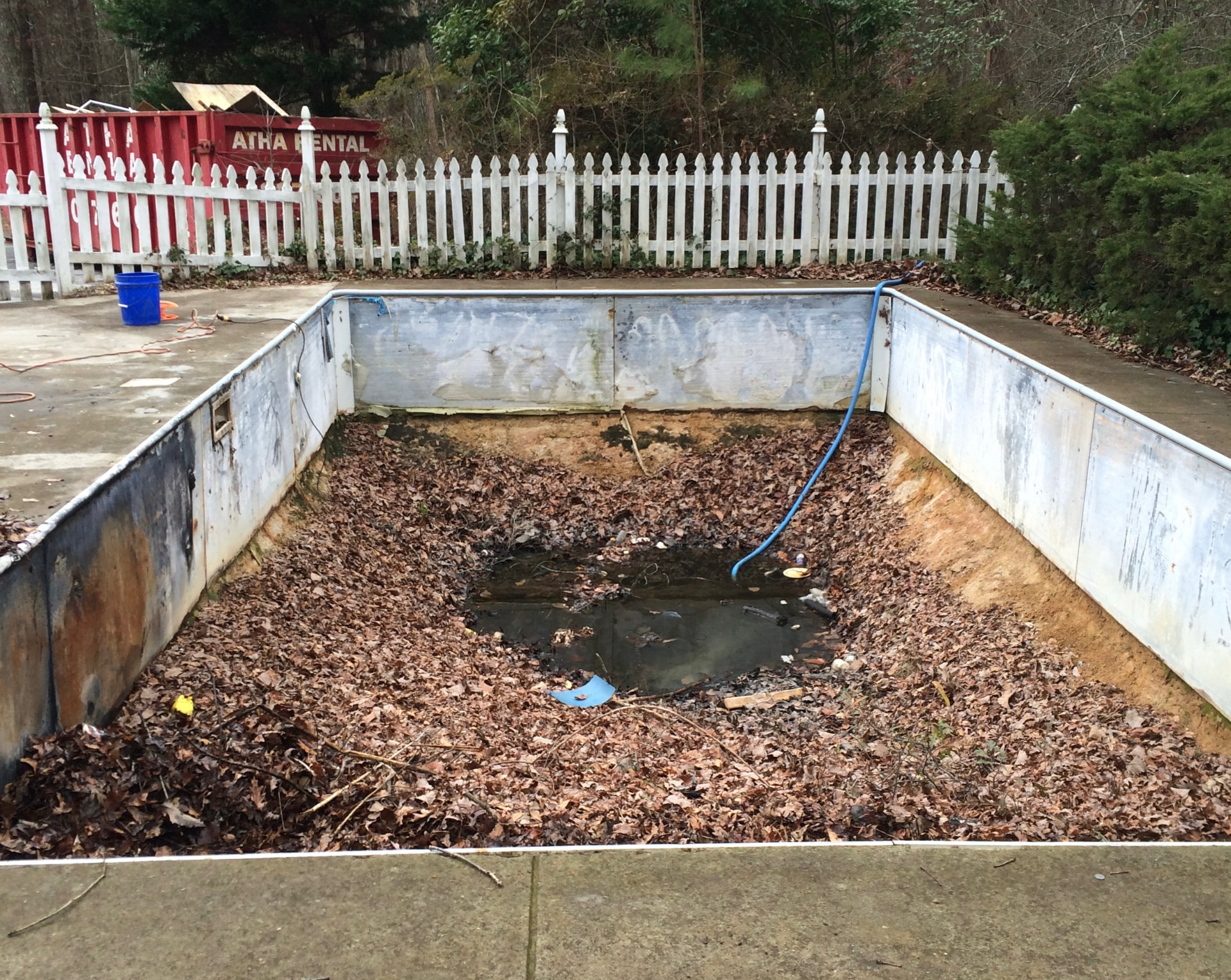 Athens, GA in-ground pool with the old vinyl swimming pool liner removed, bare walls and leaves in the deep end