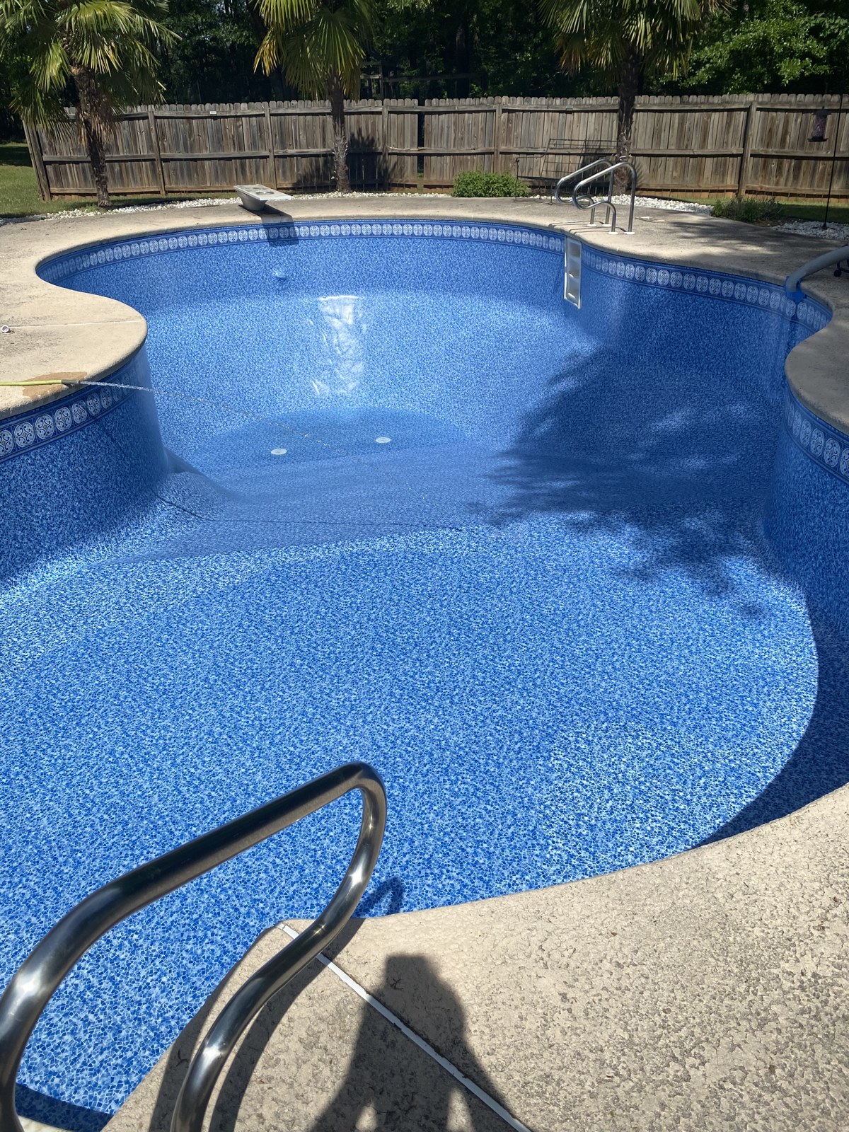 The same freeform pool filled with water after a new patterned vinyl liner install