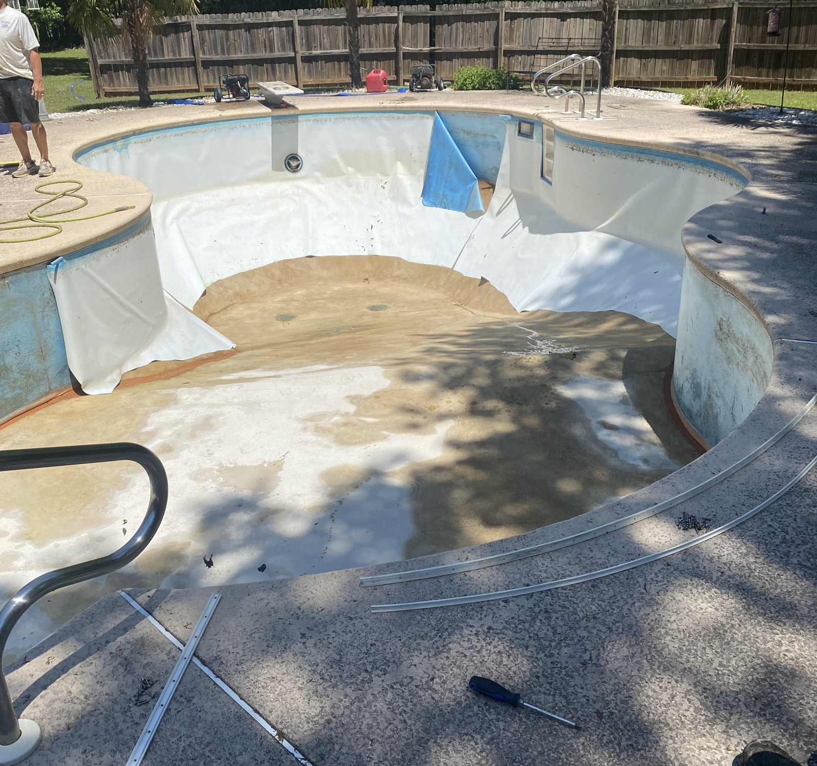 Drained freeform inground pool with the old liner stripped out before replacement
